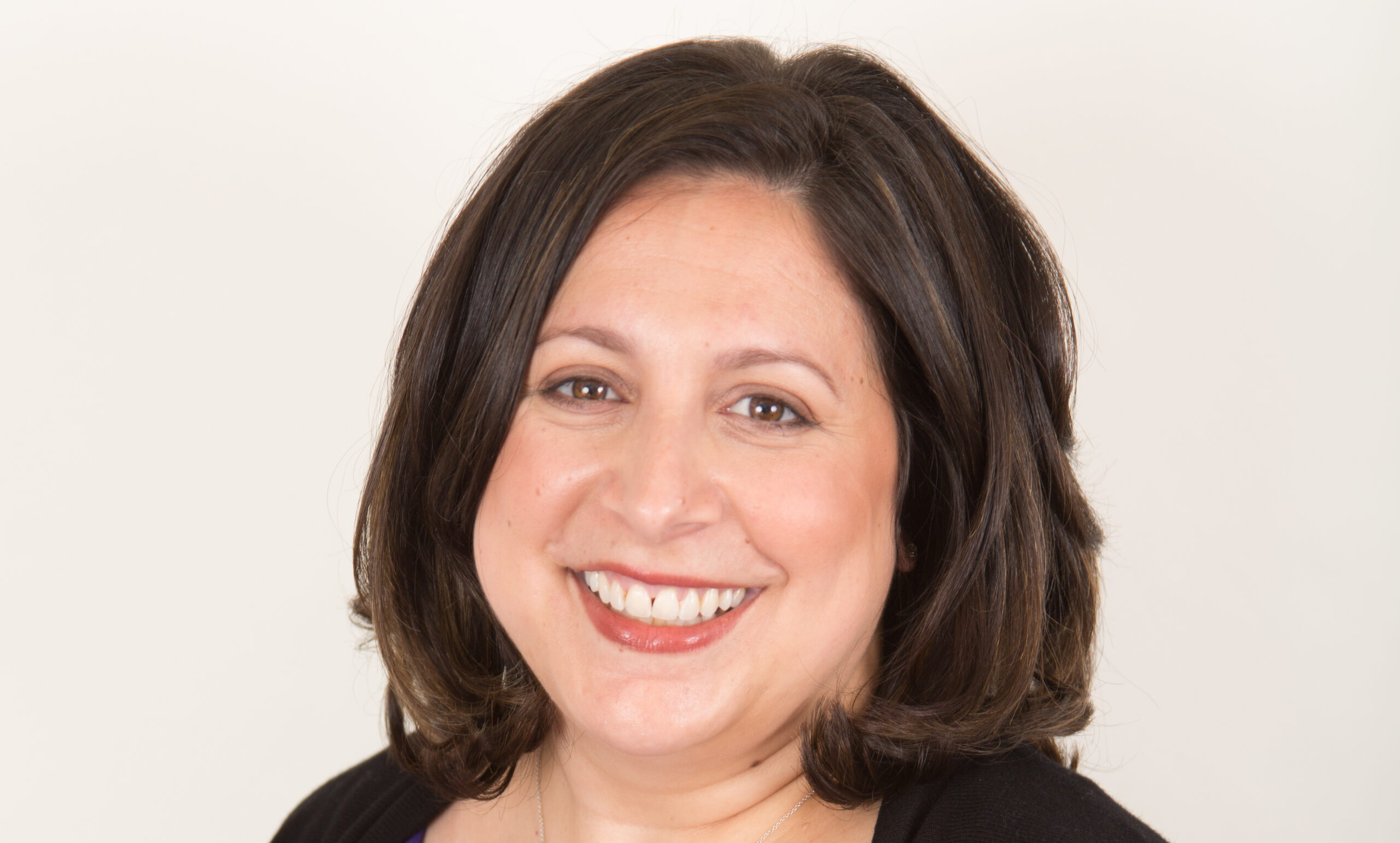 A smiling woman with medium-length dark hair wearing a black top, against a plain light background. She appears cheerful and approachable as the newest partner at Haber Silver Russoniello & Dunn.