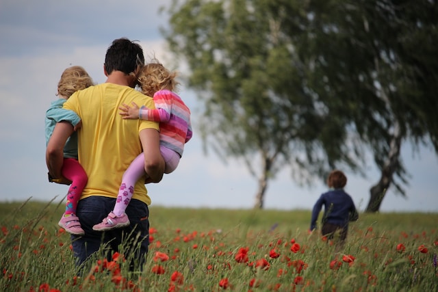 man in yellow shirt holding children