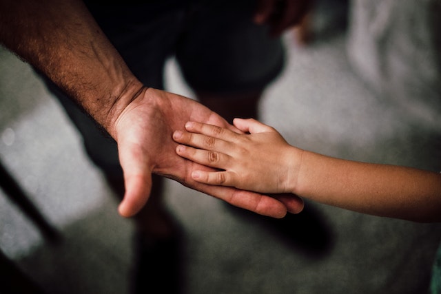 child placing hand on parent's hand