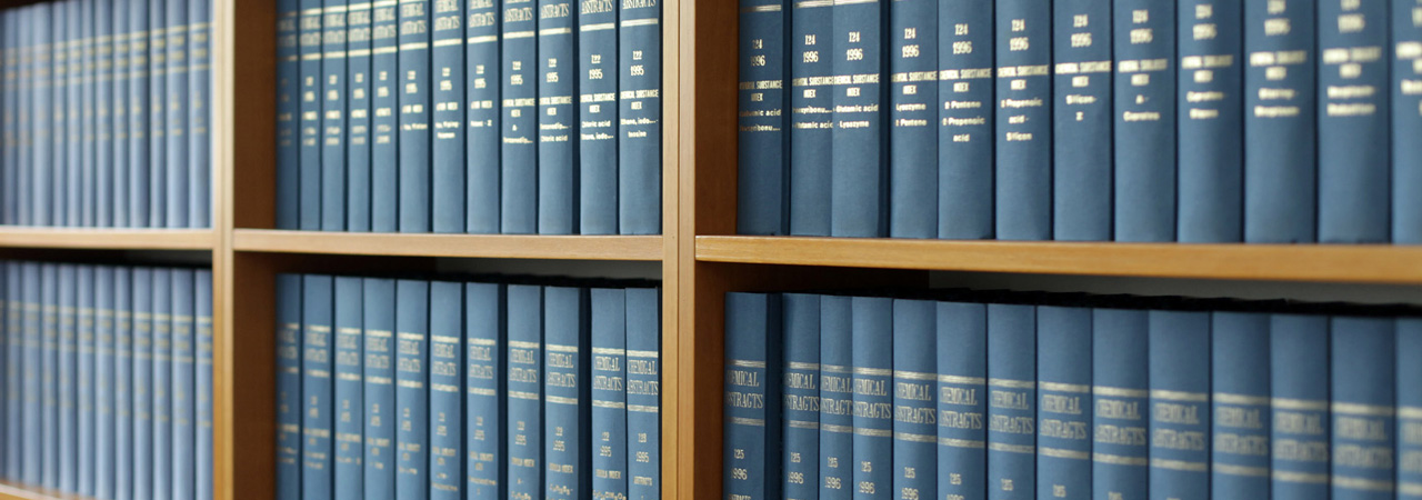 A series of wooden shelves containing numerous blue books with gold lettering, organized in a Disclaimer setting.