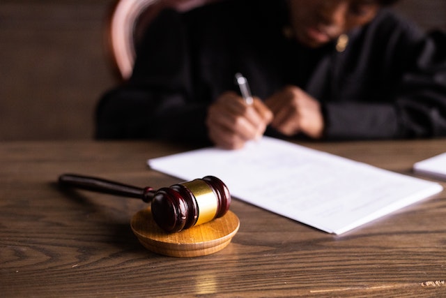 judge signing paper on desk with gavel in foreground
